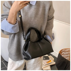 Détail du sac à main en cuir noir avec texture grainée et boucles métalliques dorées