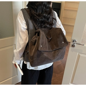 Detail of dark brown vintage backpack showing oversized flap and silver metal snaps on back