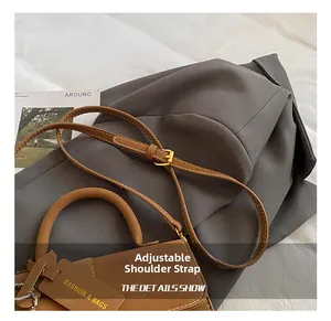 Detail of brown leather bag showing adjustable shoulder strap with gold metal buckle