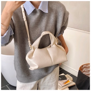 Detail of beige lychee pattern leather handbag with cloud pleats and gold hardware