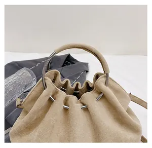 Detail of beige suede bucket bag with drawstring and silver metal round handle