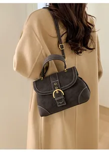 Dark grey suede crossbody bag with contrast stitching shown on a beige wool coat