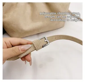 Detail of adjustable beige suede shoulder strap with silver metal buckle on bag