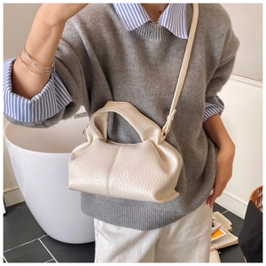 Détail du sac nuage beige texture litchi avec bandoulière porté par un mannequin