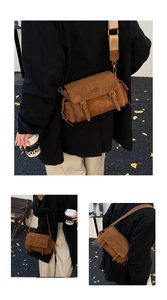 Detail of vintage brown suede messenger bag with dual metal buckles and wide strap
