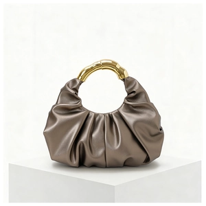 Detail of bronze pleated cloud handbag with elegant gold metal handle for evening wear