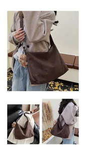 Detail of dark brown suede dumpling bag with wide strap and cute plush bear charm