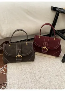 Detail of retro suede handbags with white stitching and gold buckles in deep brown and wine red