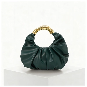 Detail of dark green ruched cloud bag with golden bamboo-shaped metal handle