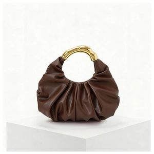 Detail of brown pleated cloud bag featuring a unique curved gold metallic handle