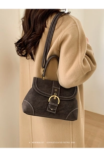 Detailed view of retro leather handbag with white contrast stitching and gold buckle