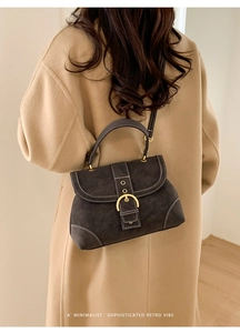 Detailed view of suede shoulder bag with contrast stitching and gold metal clasp