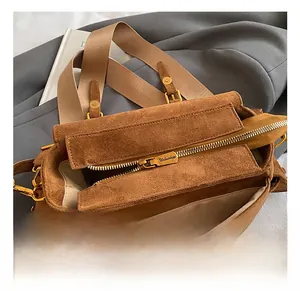 Macro shot of retro gold hardware and zipper detail on a dark brown suede Boston bag