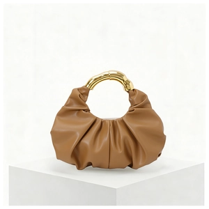 Detail of caramel pleated cloud handbag with unique artistic gold metal handle