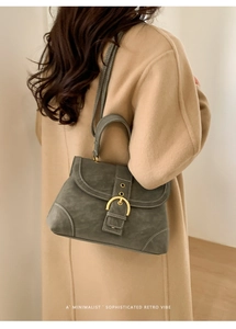 Detail of green leather handbag featuring a golden horseshoe buckle and white stitching
