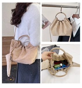 Detail of khaki suede bucket bag with metal ring handle and spacious drawstring interior