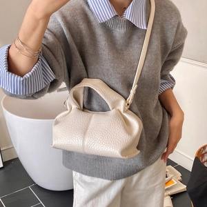 Detail of beige lychee grain leather handbag featuring soft pleats and shoulder strap