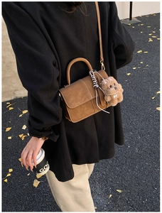 Details der kaffeebraunen matten Ledertasche mit weißen Nähten und Welpen-Anhänger