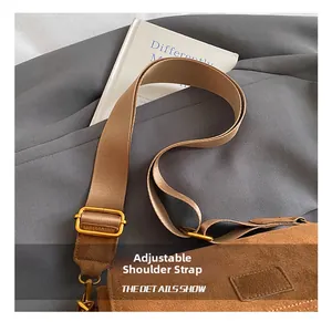 Adjustable brown suede shoulder strap with bronze metal buckle on a Boston bag