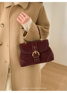 Detail of burgundy vintage handbag featuring metallic ring buckle and white contrast stitching