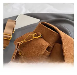 Close-up of golden metal swivel hook and brown suede texture on a crossbody bag