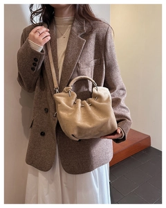 Detail of soft pleated bucket bag with round metal handle and adjustable strap