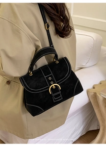 Detail of black retro handbag with contrast stitching and golden buckle on model