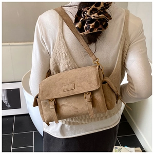 Detailed view of the khaki suede messenger bag with dual buckles and side pocket