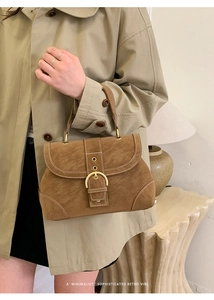 Detail shot of a brown retro handbag with matte leather and large gold buckle