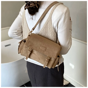 Detail of khaki suede messenger bag with double buckles and adjustable strap on a model