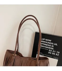 Close-up of dual shoulder straps and soft suede texture on a brown fringe tote bag