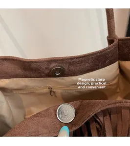 Detail view of brown suede tote bag featuring internal magnetic snap and zip pocket