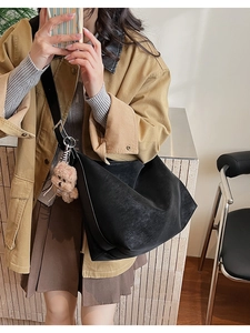 Detail of black matte PU tote bag with wide shoulder strap and cute plush bear charm