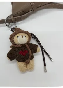 Detailed macro shot of a plush bear charm with knit heart sweater on a leather bag