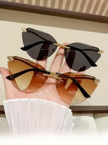 Detail of rimless cat-eye sunglasses with gold metal snake temples and tinted lenses