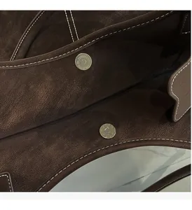 Close-up of magnetic clasps and white stitching on vintage brown leather tote bag