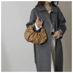 Détail d'un sac nuage plissé marron avec une poignée métallique dorée sur modèle