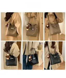 Detail of large tote bag with textured leather, bow metal buckle and cute bear charm