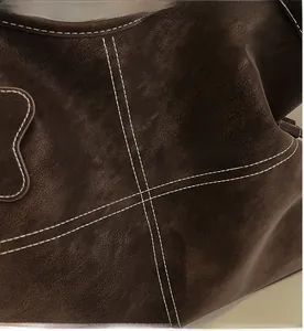 Detailed macro view of dark brown leather handbag with contrast white double stitching