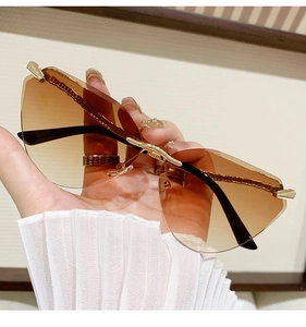 Detail of rimless cat-eye sunglasses with brown gradient lenses and gold metal temples