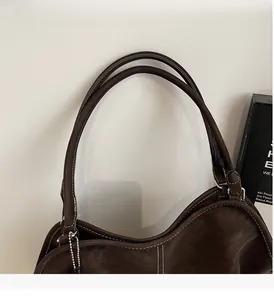Close-up of vintage brown leather tote bag handles with white contrast stitching