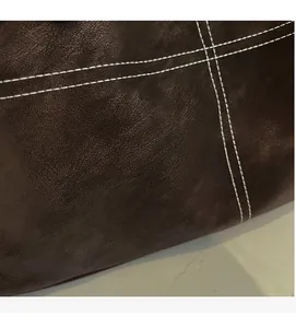 Macro shot of high-quality dark brown leather texture with contrast stitching details