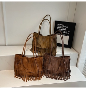 Three shades of suede tassel tote bags displayed on minimalist white stairs