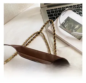 Detail of the brown suede handbag showing the metal chain shoulder strap and texture