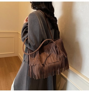 Detail view of brown suede tote bag with long bohemian tassels and shoulder strap