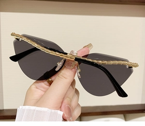 Detail of dark gray cat-eye sunglasses with golden spiral textured metal temples