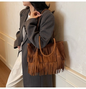 Gros plan d'un sac cabas en daim marron à longues franges porté par un mannequin
