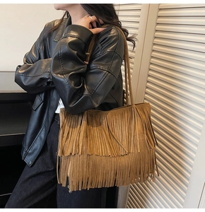 Dettaglio della borsa tote in pelle scamosciata marrone con frange indossata da modella