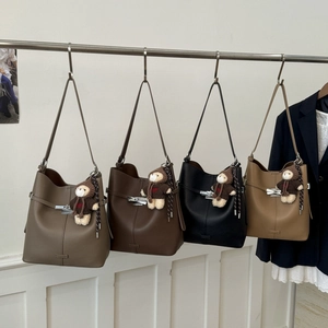 Detail of four textured leather bucket bags in various colors with cute bear charms