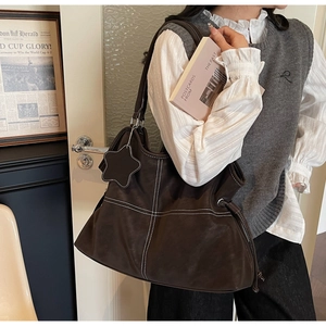 Detail of dark brown leather tote with white contrast stitching and a star charm
